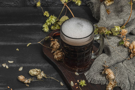 Traditional Oktoberfest composition. Dark beer, hop and wheat. German festival food concept. Trendy hard light, dark shadow, vintage black background, copy spaceの写真素材