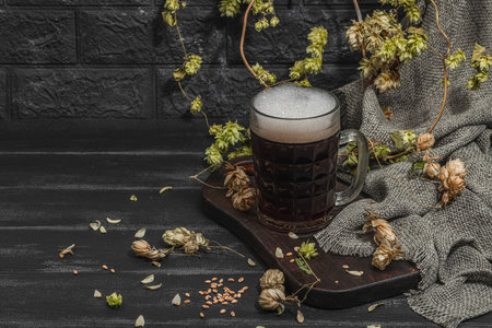 Traditional Oktoberfest composition. Dark beer, hop and wheat. German festival food concept. Trendy hard light, dark shadow, vintage black background, copy spaceの写真素材