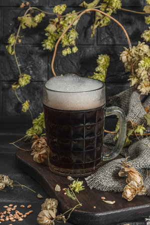 Traditional Oktoberfest composition. Dark beer, hop and wheat. German festival food concept. Trendy hard light, dark shadow, vintage black background, close upの写真素材