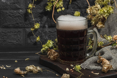 Traditional Oktoberfest composition. Dark beer, hop and wheat. German festival food concept. Trendy hard light, dark shadow, vintage black background, copy spaceの写真素材