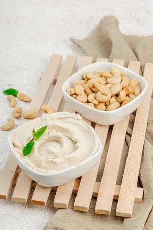Homemade vegan cashew cheese. Raw healthy sauce in a bowl, lactose free food. Bio organic product, plant based diet, alternative lifestyle. Light stone background, close upの写真素材