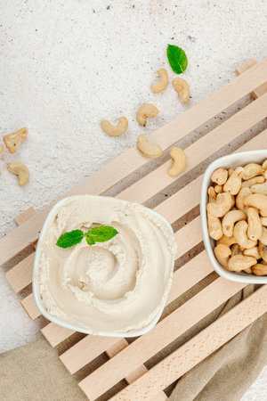 Homemade vegan cashew cheese. Raw healthy sauce in a bowl, lactose free food. Bio organic product, plant based diet, alternative lifestyle. Light stone background, top viewの写真素材