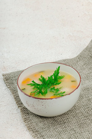 Hearty homemade Italian wedding soup with greens and meatballs. Vegetable broth with chicken and beans, comfort food. Light plaster background, copy spaceの写真素材