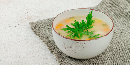 Hearty homemade Italian wedding soup with greens and meatballs. Vegetable broth with chicken and beans, comfort food. Light plaster background, banner formatの写真素材
