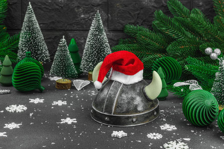 Creepy New Year concept. Handmade Viking helmet with traditional Santa Clause red hat. Christmas background, festive decoration, creative composition. Dark tones, copy spaceの写真素材
