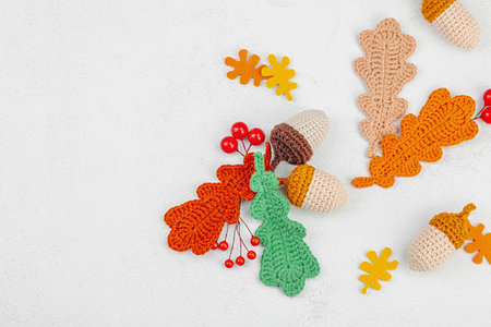 Set of traditional knitted autumn decoration. Crocheted different acorn and leaves, handmade, cozy hobby concept. Fall props on light stone background, top viewの写真素材
