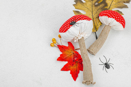 Halloween craft concept. Soft sewed fly agaric mushrooms, oak leaves, decorative berries and spiders. Light background, top viewの写真素材