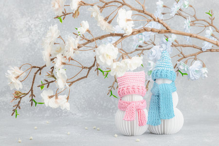 Happy snowmen under a sakura branches. Cute greeting card, Valentine's Day holiday concept, lovers anniversary, wedding. Light backgroundの写真素材