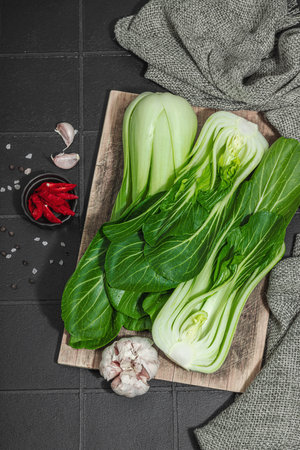 Fresh Bok choy on a trendy black tile background. Traditional Chinese cabbage is a vitamin ingredient used in cooking healthy food. Vegan lifestyle, hard light, dark shadow, flat lay, top viewの写真素材
