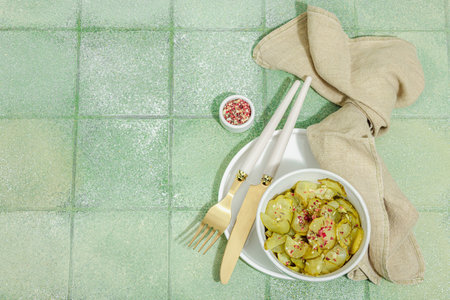 Fermented cucumbers in a bowl. Healthy gut food, natural probiotic superfoods, organic pickles vegetables. Green tile background, top viewの写真素材