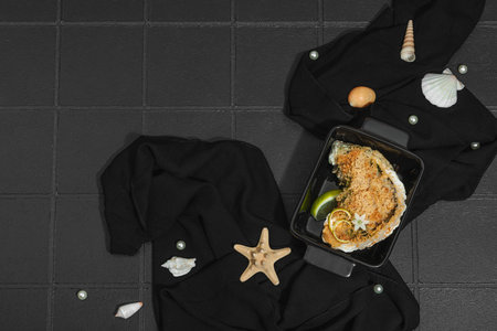 Gourmet baked oyster with herbs and cheese. Elegant seafood dish, coastal culinary delight, healthy ocean-inspired cuisine. Black tile background, marine style, top viewの写真素材