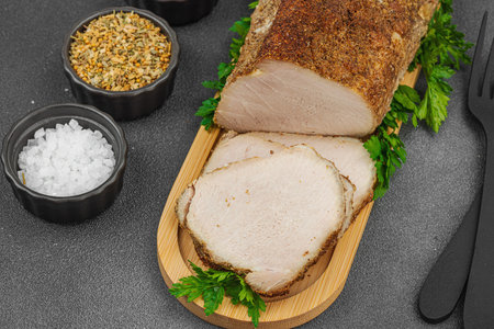 High-protein roasted pork loin served with flavor spices, styled for food photography. Suitable for keto and paleo diets, black stone background, close upの写真素材