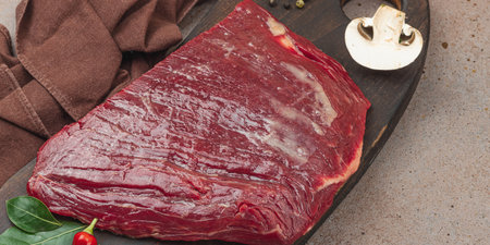 Fresh raw flank steak with assorted spices on wooden cutting board. Culinary concept for meat preparation, gourmet cooking, or food styling, banner formatの写真素材