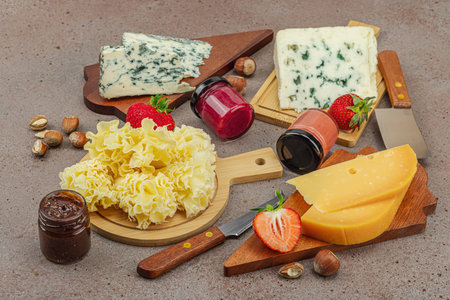 Cheese assortment on rustic background with nuts, strawberries and jam. Includes TÃªte de Moine, Roquefort, Gouda on wooden boards, close upの写真素材