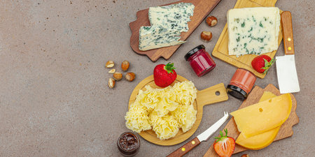 Cheese assortment on rustic background with nuts, strawberries and jam. Includes TÃªte de Moine, Roquefort, Saint Agur and Gouda on wooden boards, banner formatの写真素材