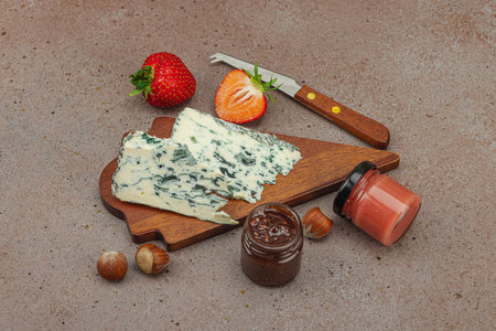 Cheese assortment on rustic background with nuts, strawberries and jam. Includes Tête de Moine, Roquefort, Saint Agur and Gouda on wooden boards, copy spaceの写真素材