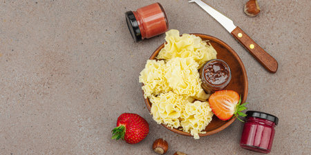 Cheese assortment on rustic background with nuts, strawberries and jam. Includes Tête de Moine, Roquefort, Saint Agur and Gouda on wooden boards, banner formatの写真素材