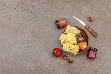 Cheese assortment on rustic background with nuts, strawberries and jam. Includes Tête de Moine, Roquefort, Gouda on wooden boards, top viewの写真素材