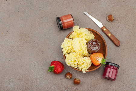 Cheese assortment on rustic background with nuts, strawberries and jam. Includes Tête de Moine, Roquefort, Saint Agur and Gouda on wooden boards, top viewの写真素材
