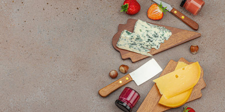 Cheese assortment on rustic background with nuts, strawberries and jam. Includes TÃªte de Moine, Roquefort, Saint Agur and Gouda on wooden boards, banner formatの写真素材