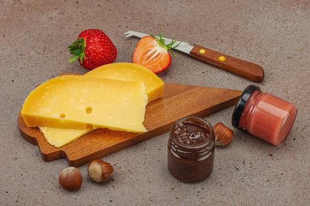 Cheese assortment on rustic background with nuts, strawberries and jam. Includes TÃªte de Moine, Roquefort, Gouda on wooden boards, copy spaceの写真素材