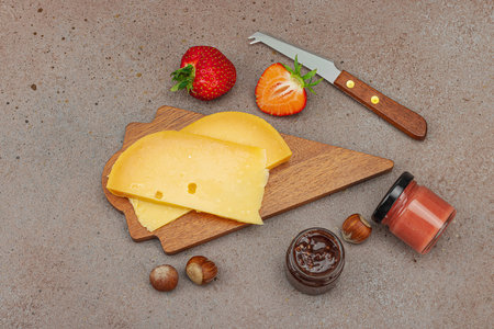 Cheese assortment on rustic background with nuts, strawberries and jam. Includes TÃªte de Moine, Roquefort, and Gouda on wooden boards, top viewの写真素材