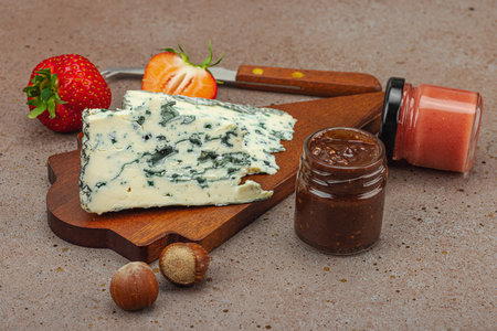 Cheese assortment on rustic background with nuts, strawberries and jam. Includes Roquefort, Gouda on wooden boards, copy spaceの写真素材