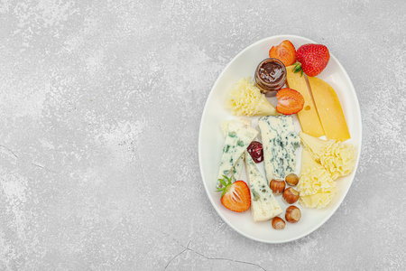 Cheese assortment on rustic background with nuts, strawberries and jam. Includes Roquefort and Gouda on wooden boards, top viewの写真素材