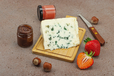 Cheese assortment on rustic background with nuts, strawberries and jam. Includes Roquefort, and Gouda on wooden boards, top viewの写真素材