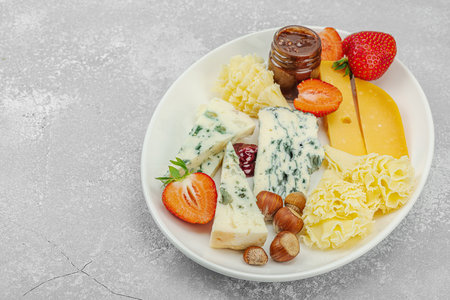 Cheese assortment on rustic background with nuts, strawberries and jam. Includes Tête de Moine, Roquefort, Saint Agur and Gouda on wooden boards, copy spaceの写真素材