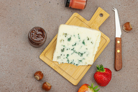 Cheese assortment on rustic background with nuts, strawberries and jam. Includes Roquefort and Gouda on wooden boards, top viewの写真素材