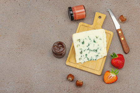 Cheese assortment on rustic background with nuts, strawberries and jam. Includes Roquefort, Gouda on wooden boards, top viewの写真素材