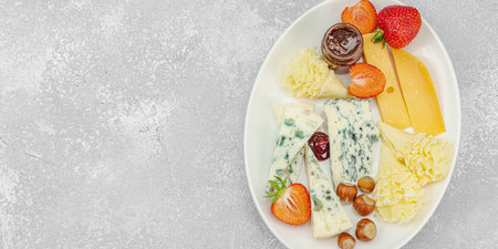 Cheese assortment on rustic background with nuts, strawberries and jam. Includes TÃªte de Moine, Roquefort, Saint Agur and Gouda on wooden boards, banner formatの写真素材