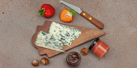 Cheese assortment on rustic background with nuts, strawberries and jam. Includes Roquefort, Saint Agur and Gouda on wooden boards, banner formatの写真素材