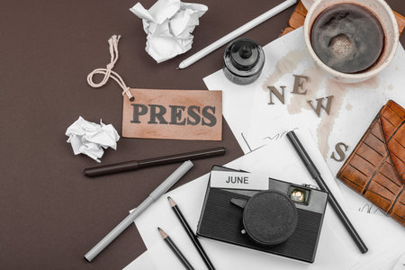 Creative flat lay with vintage camera, press tag, ink bottle, spilled coffee, and messy papers. A symbolic tribute to journalism, OSINT, and the pursuit of truth, top viewの写真素材