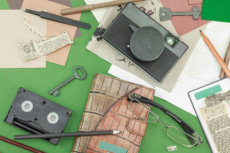 Flat lay with vintage camera, cassette, notebook, key and research tools on green background,...