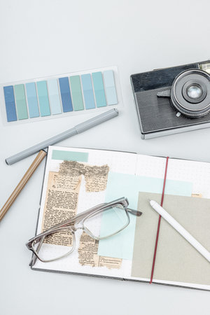 Flat lay of retro journalist essentials on white background: camera, notebook, newspaper clippings, and stationery. Media storytelling theme, top viewの写真素材