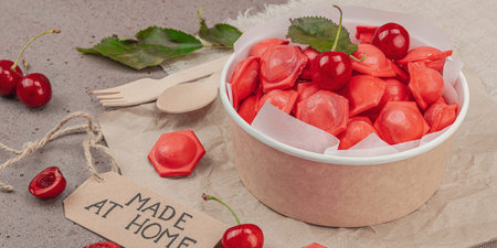 Frozen cherry dumplings in a paper bowl, flat lay composition with fresh cherries, mint, handmade label. Zero waste concept of food delivery, smart consumption, banner formatの写真素材