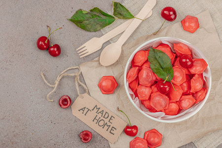 Frozen cherry dumplings in a paper bowl, flat lay composition with fresh cherries, mint, handmade label. Zero waste concept of food delivery, smart consumption, care for the environment, top viewの写真素材