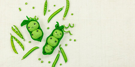 Handmade amigurumi peas with real vegetables on a neutral fabric background. Eco craft, early...