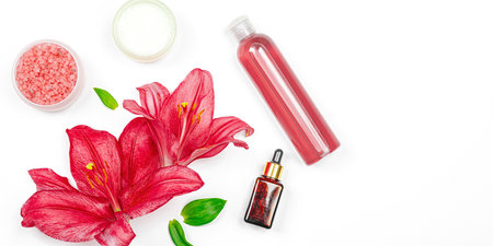 Natural cosmetic products with pink lily flowers isolated on white background. Organic skincare branding flat lay, banner formatの写真素材