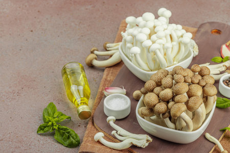 Fresh assorted shimeji mushrooms with olive oil, basil, garlic, salt, and pepper on rustic kitchen background. Vegan ingredient for healthy eating, food concept, copy spaceの写真素材