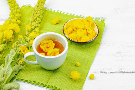 Cup of herbal tea with mullein flowers and leaves. Natural light, alternative medicine, vintage...