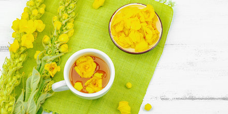 Cup of herbal tea with mullein flowers and leaves. Natural light, alternative medicine, vintage...