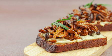 Healthy plant-based open sandwiches with sautÃ©ed Shimeji mushrooms. Protein rich vegan meal is served on a white plate, warm stone background, banner formatの写真素材