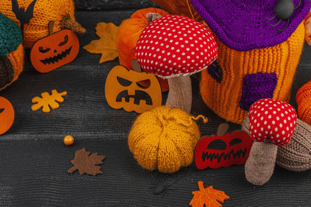 Dark Halloween atmospheric composition. Handmade knitted, crocheted, and sewn autumn decor. Pumpkins, mushrooms, fall leaves, Jack o lanterns, berries. Creative festive hobby, DIY decorationsの写真素材