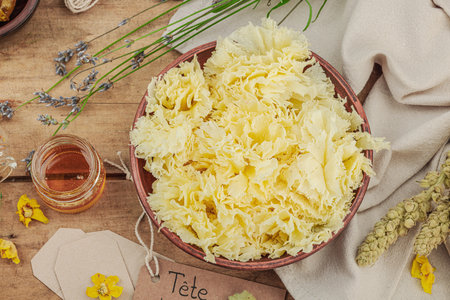 Rustic still life with cheese, honey, and dried herbs on a wooden table. Warm light and vintage atmosphere in apothecary style, flat lay, top viewの写真素材