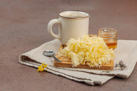 Cheese rosettes served with honey and coffee in a rustic morning setup on linen fabric and wooden...