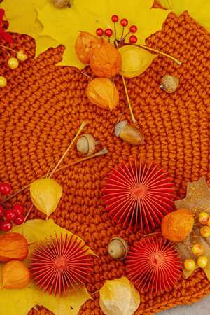 Autumn still life with red paper pumpkins, acorns, yellow maple leaves, and physalis on a textured background. Cozy seasonal composition, slow living style, top viewの写真素材