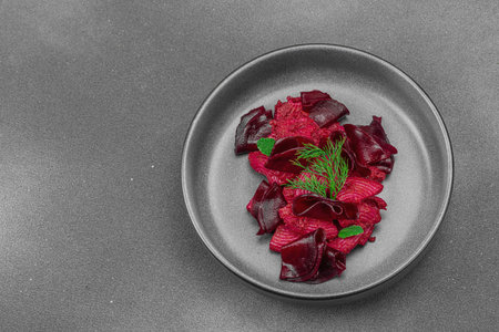 Vegan beetroot pasta with fresh dill and mint served in a trendy dark ceramic bowl. Healthy,...